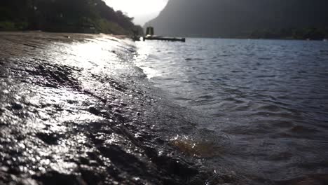 Slomo-Nahaufnahme-Von-Wasser,-Das-Gegen-Sonnenuntergang-Auf-Das-Ufer-Trifft