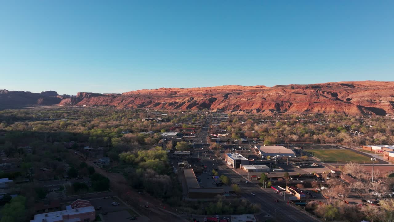 un avión no tripulado volando directamente sobre el centro de moab, utah al atardecer.