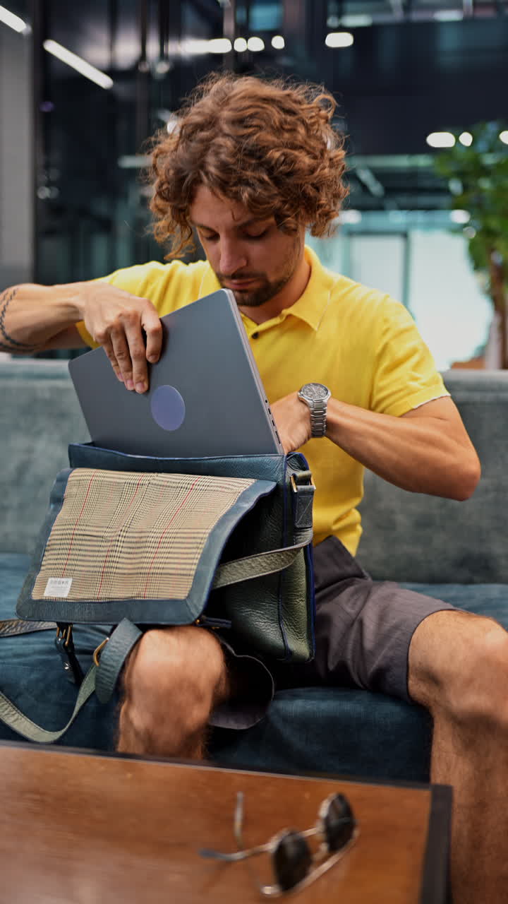 Man in yellow shirt packing up his things and going home from work. Vertical