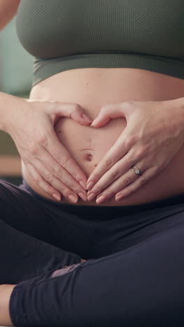 mujer embarazada haciendo forma de corazón con las manos en el vientre