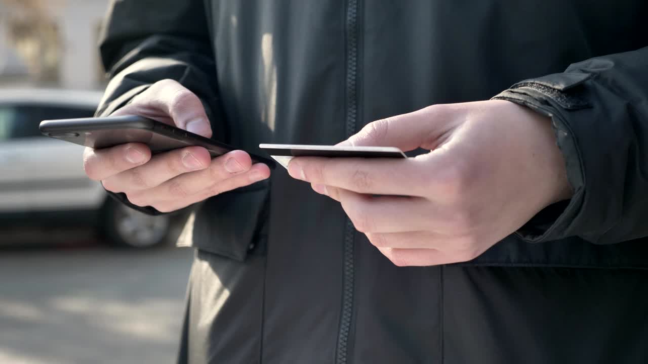 남자 손은 큰 검은 스마트폰과 신용카드, 온라인 은행, 쇼핑, 온라인 상점 60fps를 들고 있습니다.