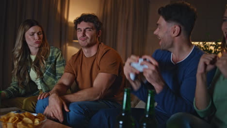 enthusiastic team playing video games on room couch close up. excited friends