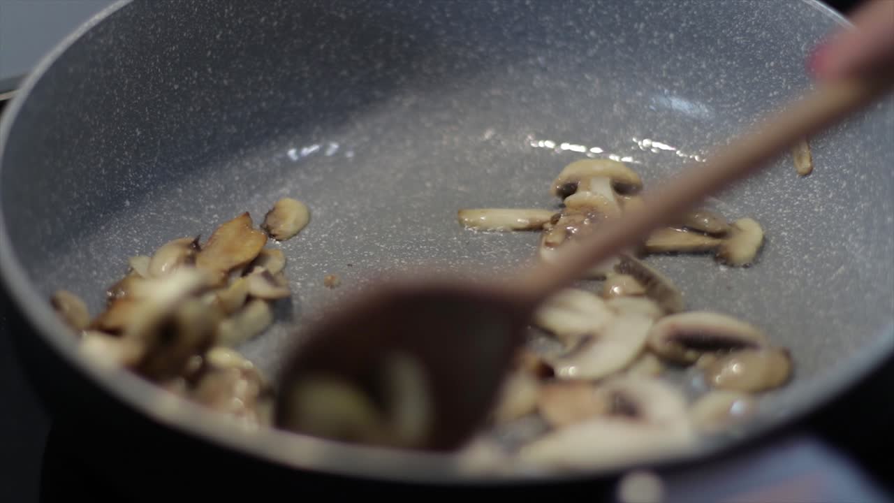 Sauteing Sliced Mushrooms In A Skillet With Small Amount Of Cooking Oil - close up