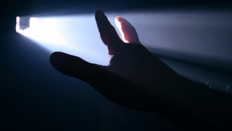hombre sosteniendo su mano contra un rayo de luz