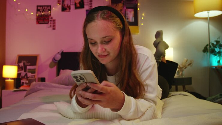 Donna sdraiata a letto che usa il telefono