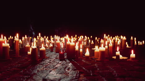 a field of burning candles in the dark