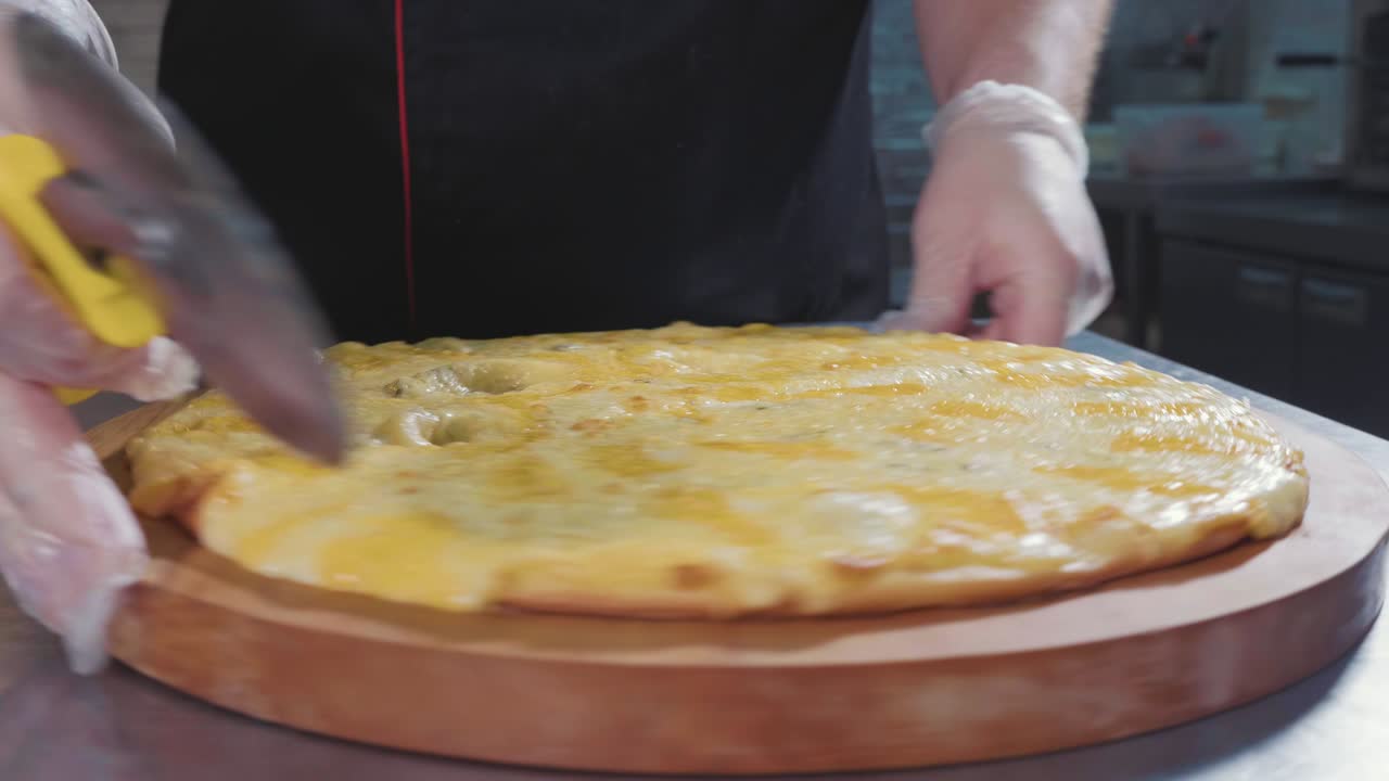 Chef che taglia una pizza calda appena sfornata con un tagliapizza a rotella, primo piano al rallentatore