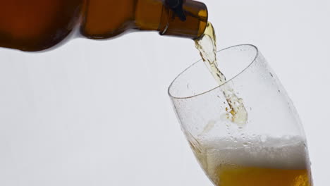 fresh beer spilling bottle to glass in super slow motion closeup. lager beverage