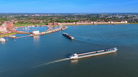 two long empty barges near the port of lelystad, the netherlands. aerial perspective on the waterfront of lake markermeer with lush greenery.