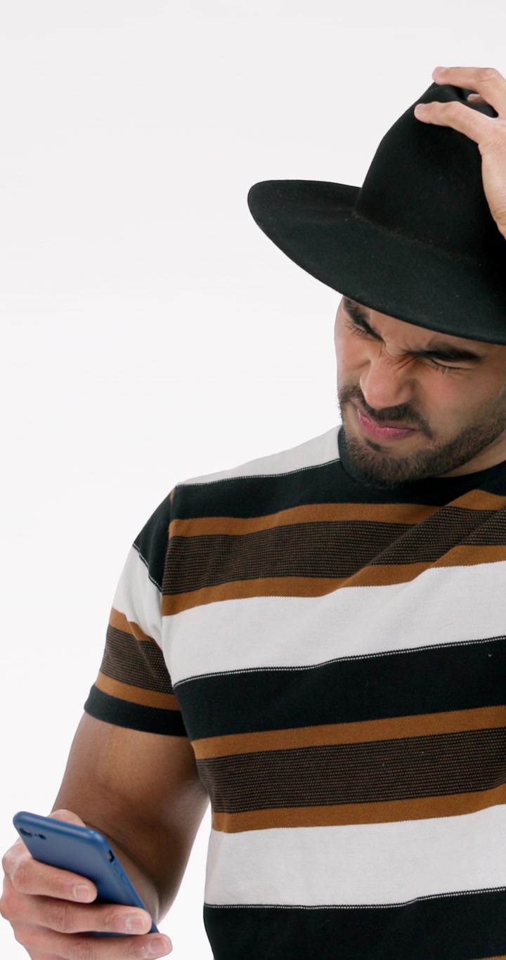 Giovane uomo con cappello guarda il suo smartphone