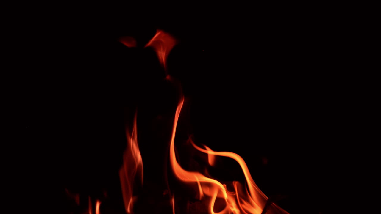 Beautiful flames of bonfire dancing in the darkness. Thin tongues of flame going up. Close up.
