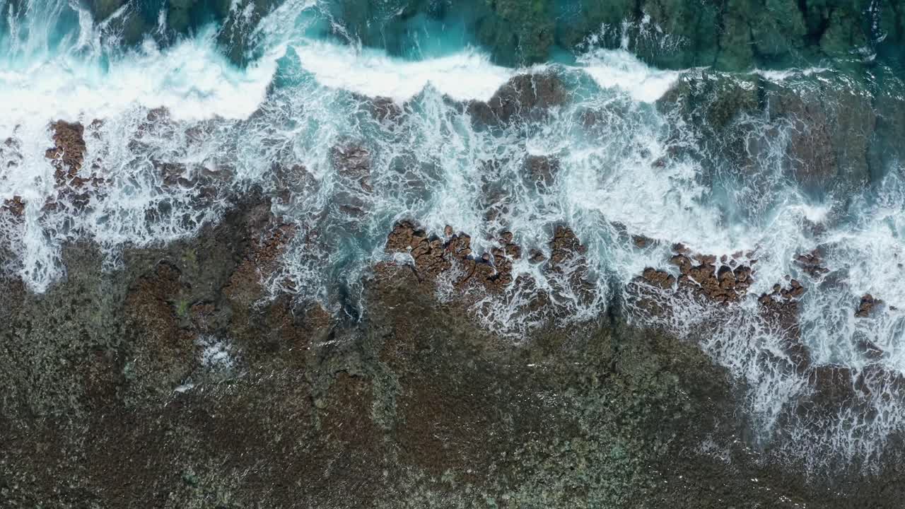 Vista aerea dall'alto di onde marine che si infrangono sulla barriera corallina vicino a un'isola tropicale