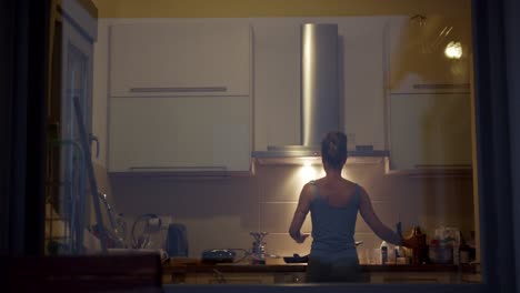 rear view of a woman cooking in the kitchen at night