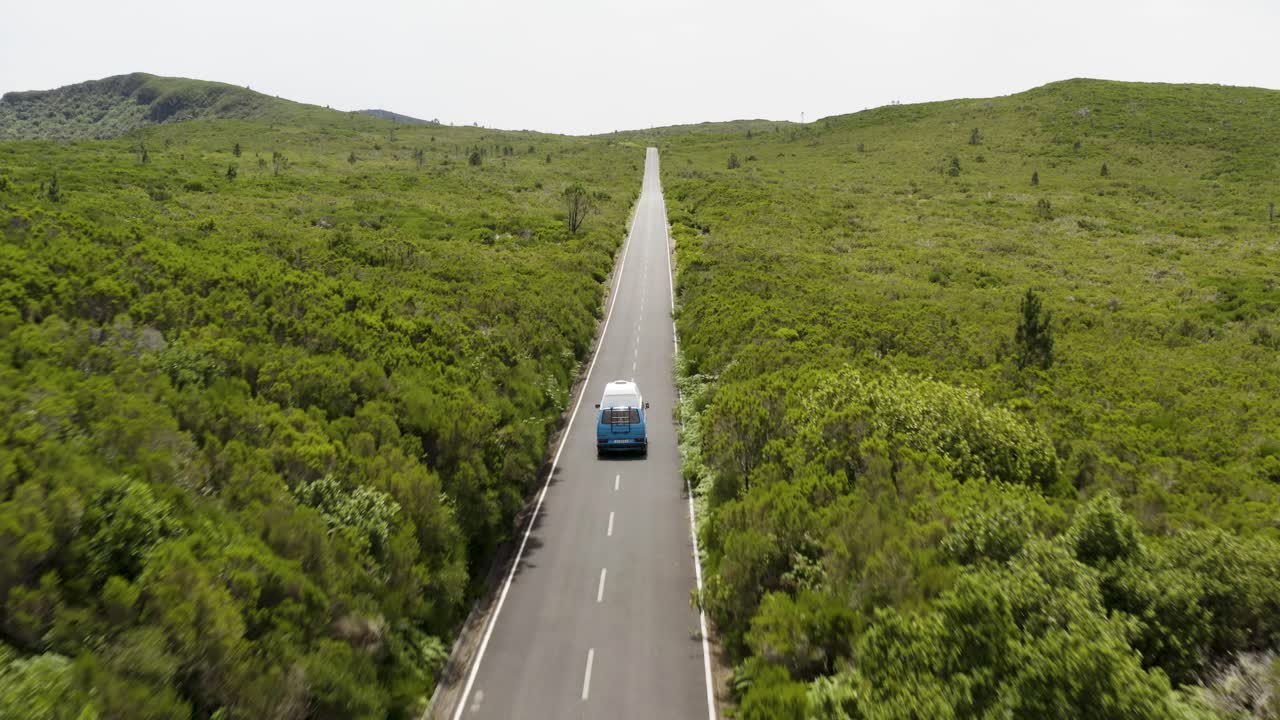 Splendida ripresa aerea che segue un furgone VW-Camper su una strada panoramica di giorno a Madeira, Portogallo.