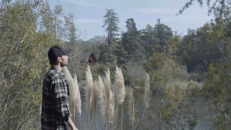 man lifts arms over beautiful lake