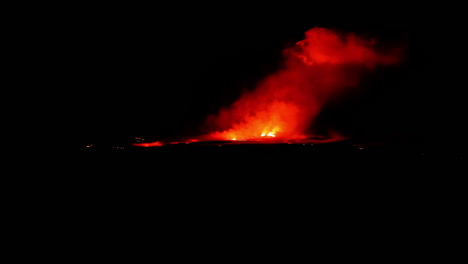 fire and a cloud of smoke rising in the darkness. volcano eruption in iceland. dangerous travel destination.
