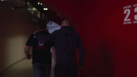 two men walking in a stadium hallway