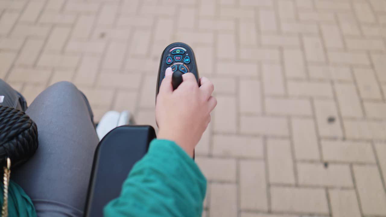 Primo piano di una mano che aziona il joystick di una sedia a rotelle elettrica