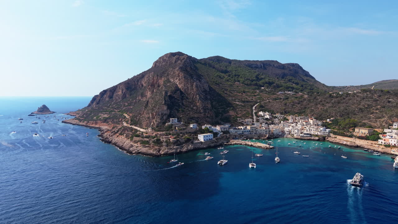 Aerial view of a coastal village with boats near a mountain