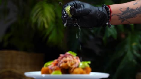 chef with glove squeeze lemon on top of blur taco