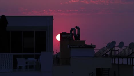 the sun at sunset hiding behind the tall buildings