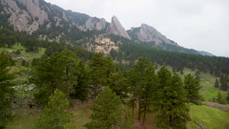 Aerial-flyover-trees-toward-Flatirons-rock-formation,-Boulder,-Colorado