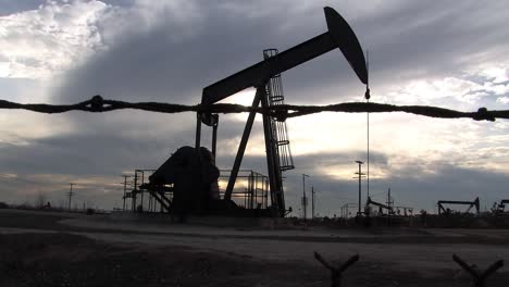 Oil-field-with-oil-pumps-in-Los-Angeles-in-the-evening-behind-barb-wire,-California,-USA