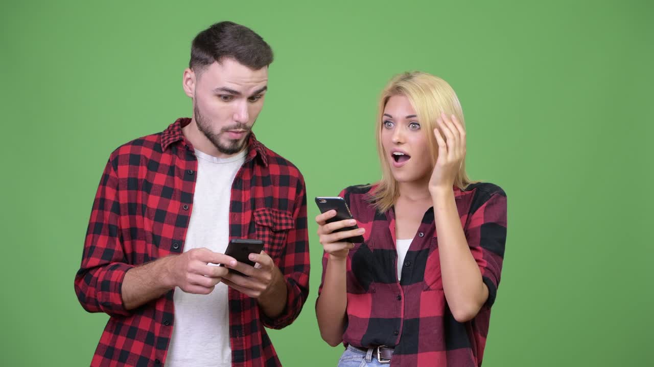 Young couple using phone and looking surprised together