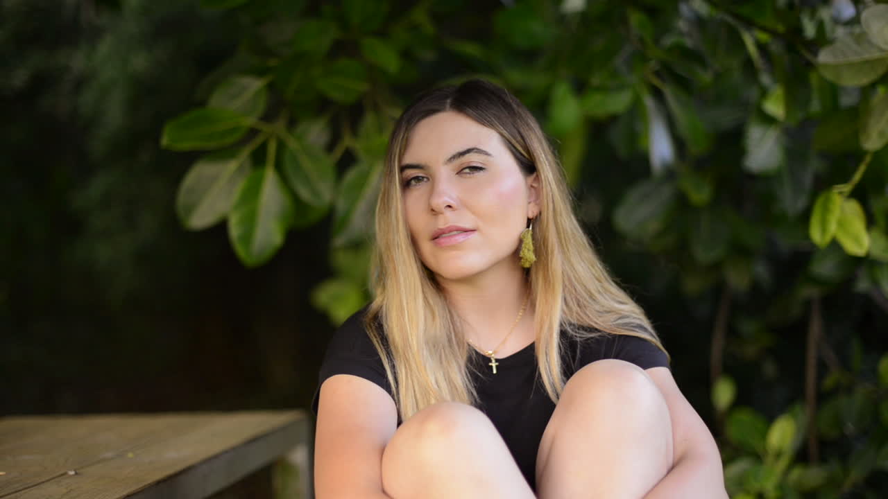 tierna, inocente, dulce mujer hermosa pensando en el parque, se vuelve hacia la cámara y sonríe