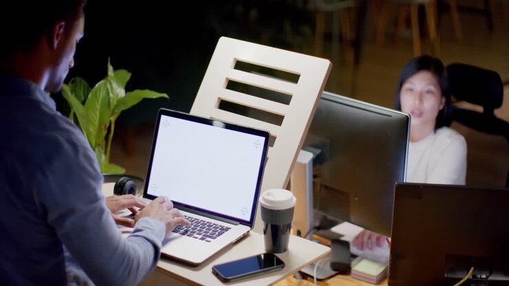 Diverse mandlige og kvindelige kolleger bruger bærbar computer med plads til tekst og telefon sent på kontoret, i slowmotion.