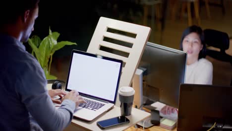 diverse male and female colleague using laptop with copy space and phone late in office, slow motion