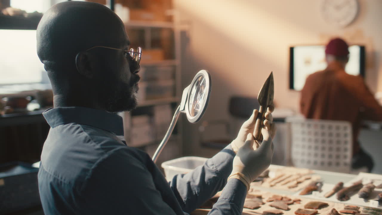 Black Archaeologist Examining Spearhead during Lab Research