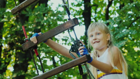 entretenimiento en el campamento de verano - un niño aprende a usar cables de seguros trepa alto en las ramas de