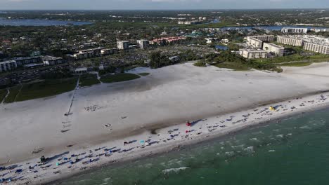 waves lap the Siesta Key beach coasline, aerial flight over public park and parking lot