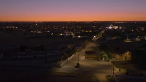 Aerial-of-empty-residential-streets-illuminated-by-street-lights-at-dusk-with-beautiful-golden-sunset-sky