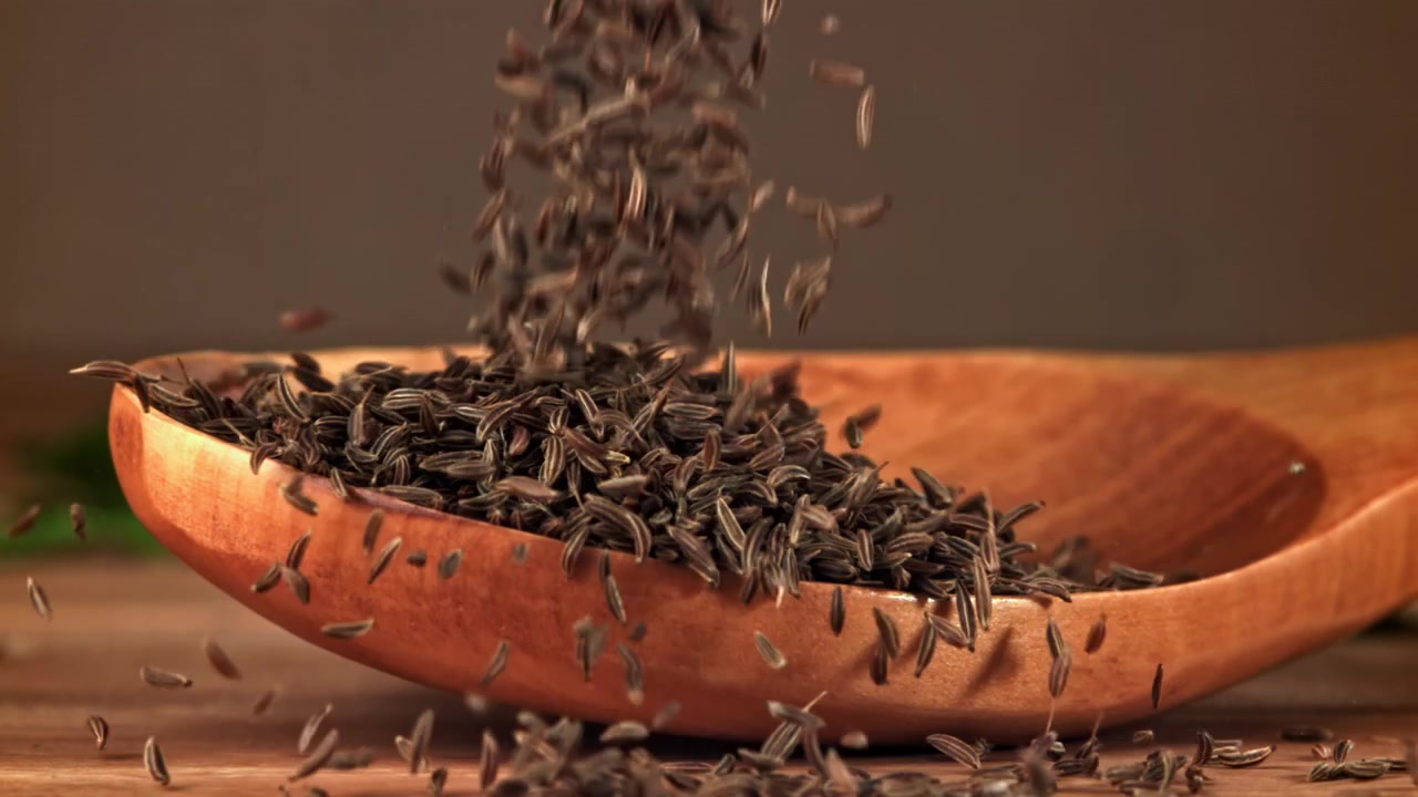 Cumin Seeds Falling into a Wooden Spoon in Slow Motion