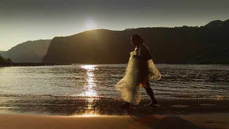 Classic-shot-of-Polynesian-fisherman-walking-on-a-beach-with-his-fishing-net