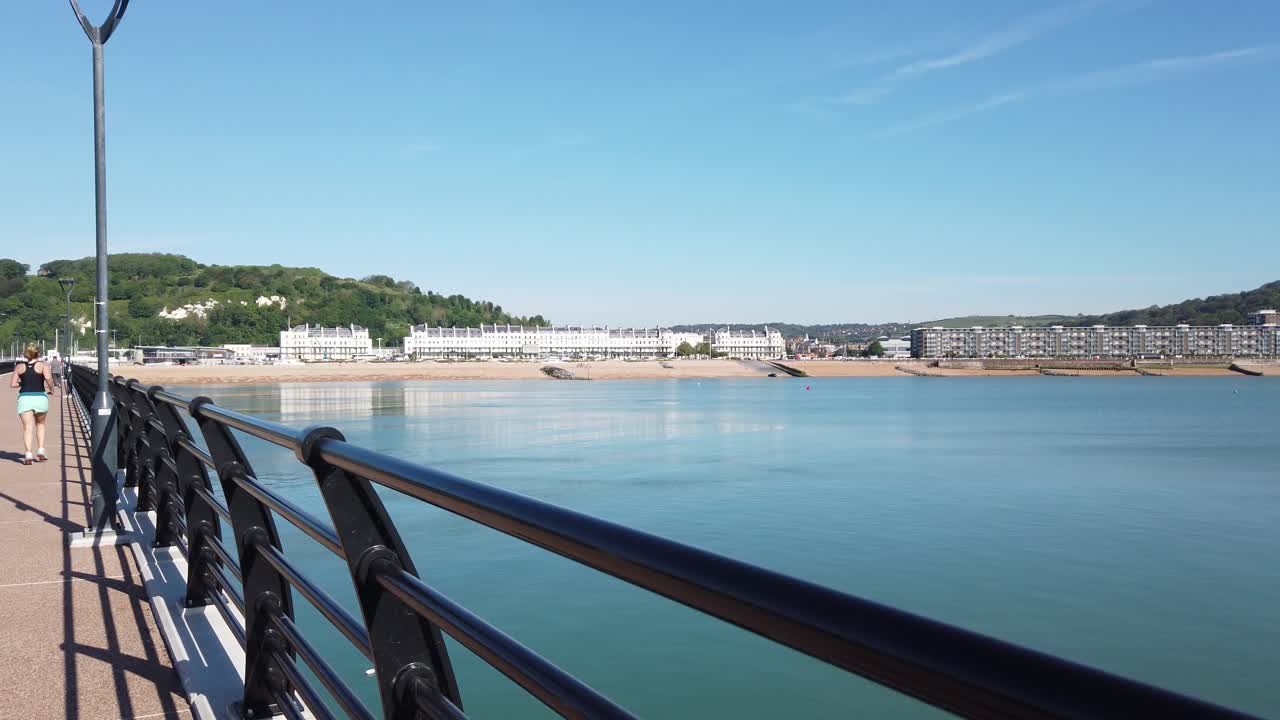 Joggers run down the Dover jetty in the morning on a summer day