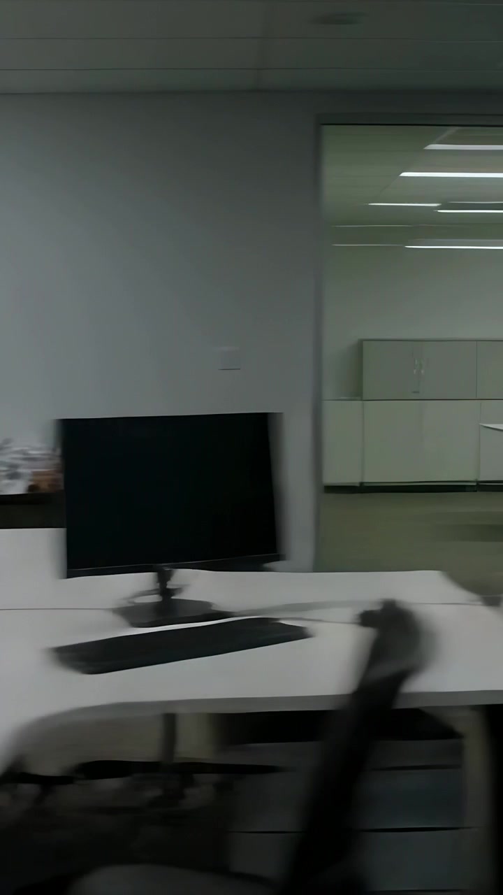 Vertical video: Camera panning row of desks and monitors across office, revealing crumpled paper