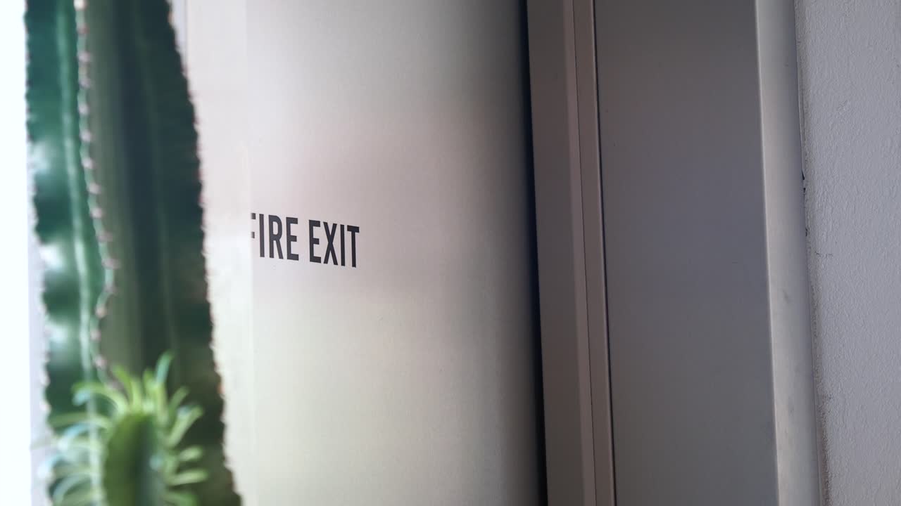 A close-up of a fire exit sign on a white door