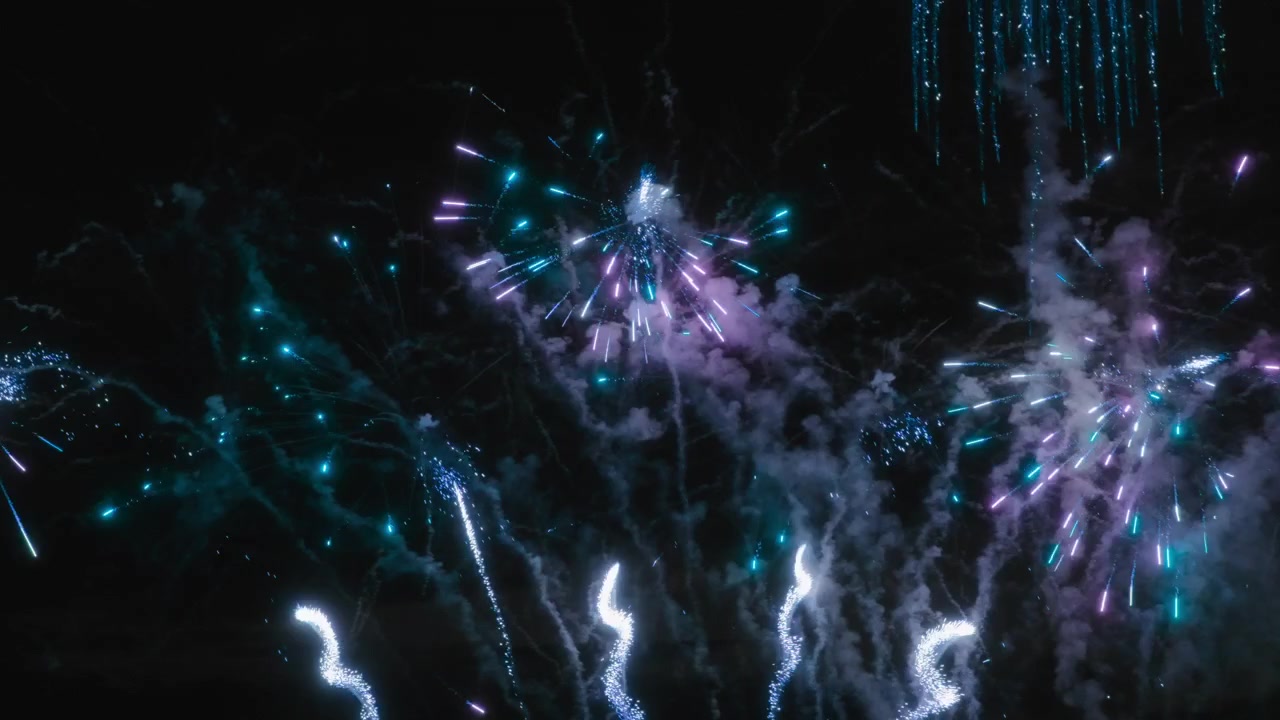 Fuochi d'artificio blu e viola che esplodono nel cielo notturno durante una celebrazione.