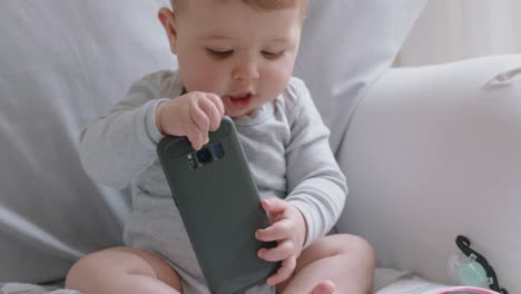 funny baby playing with smartphone toddler looking curious at phone infant learning using mobile technology at home