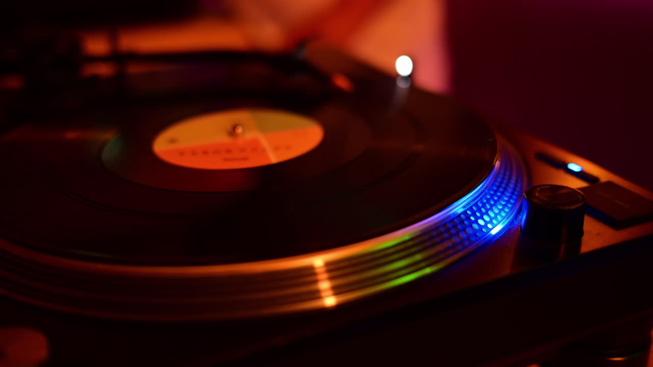 Tocadiscos reproduciendo un disco de vinilo, mostrando un ambiente de club vibrante con luces azules y naranjas