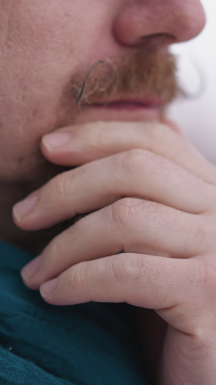 hombre con pañuelo coloca la mano en el mentón de cerca. hombre enfocado toma un momento para apreciar el paisaje cubierto de nieve fuera de la ventana en la residencia. tranquilidad disfrute