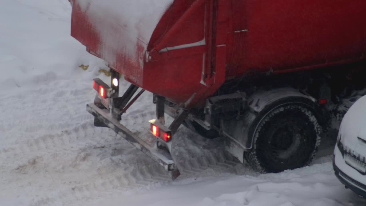 쓰레기통 트럭이 얼음 위의 눈 속에 멈춰서 겨울에 눈 폭풍, 스핀, 클로즈업.
