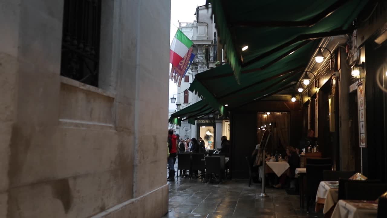 Narrow Venetian Street with Outdoor Cafe and Italian Flag