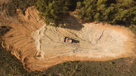 vista aérea de 4k de una excavadora moviendo algo de tierra en el medio del bosque, maquinaria pesada