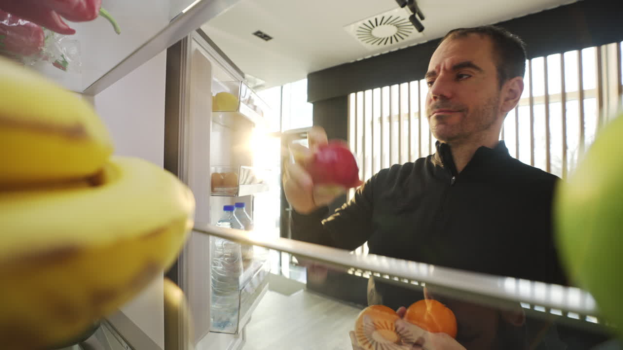 Man looking into refrigerator full of fruits