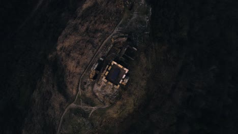 Orbiting-drone-top-view,-hilltop-medieval-Hazmburk-Castle-tower-at-dusk