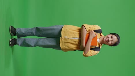 student with books on green screen